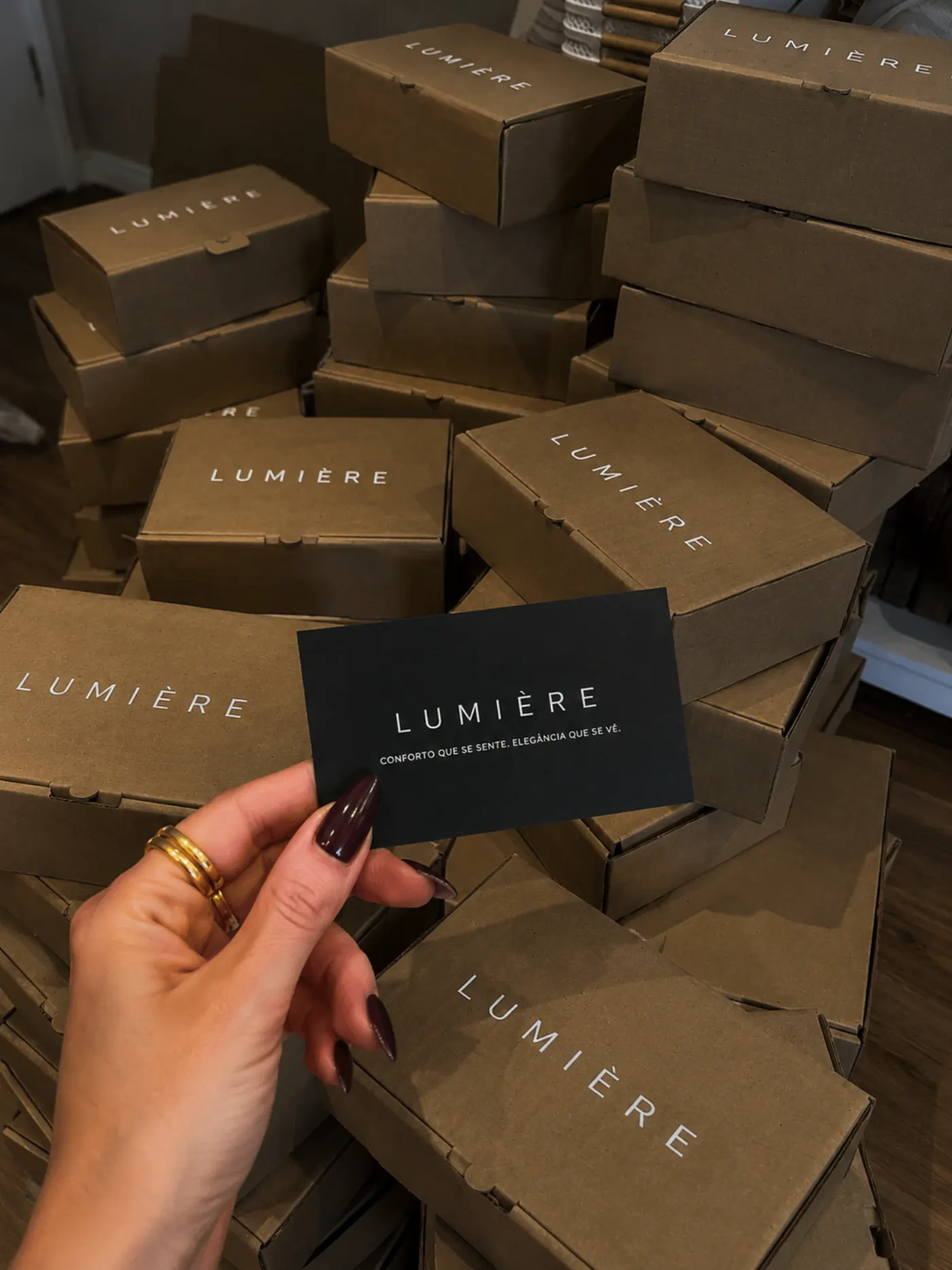 Embalagens Lumière empilhadas com cartão da marca